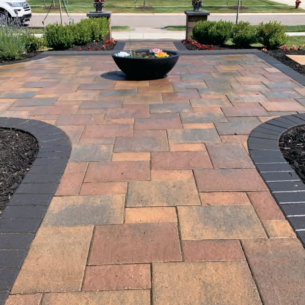 Brick walkway under construction beside a stone building, with gravel and soil base visible.